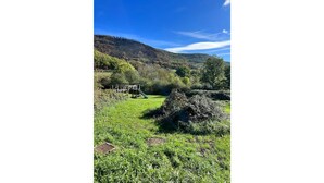 A playground with a slide and climbing structure in a grassy field with hills in the background. - Gite Herisson, Nid Pour Amoureux Dans la Nature (Avène)