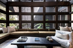 A room with a large window, a sofa, a table, and a book.