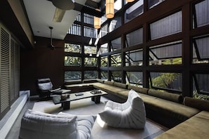 A modern interior with a large window, a sofa, a chair, and a coffee table.