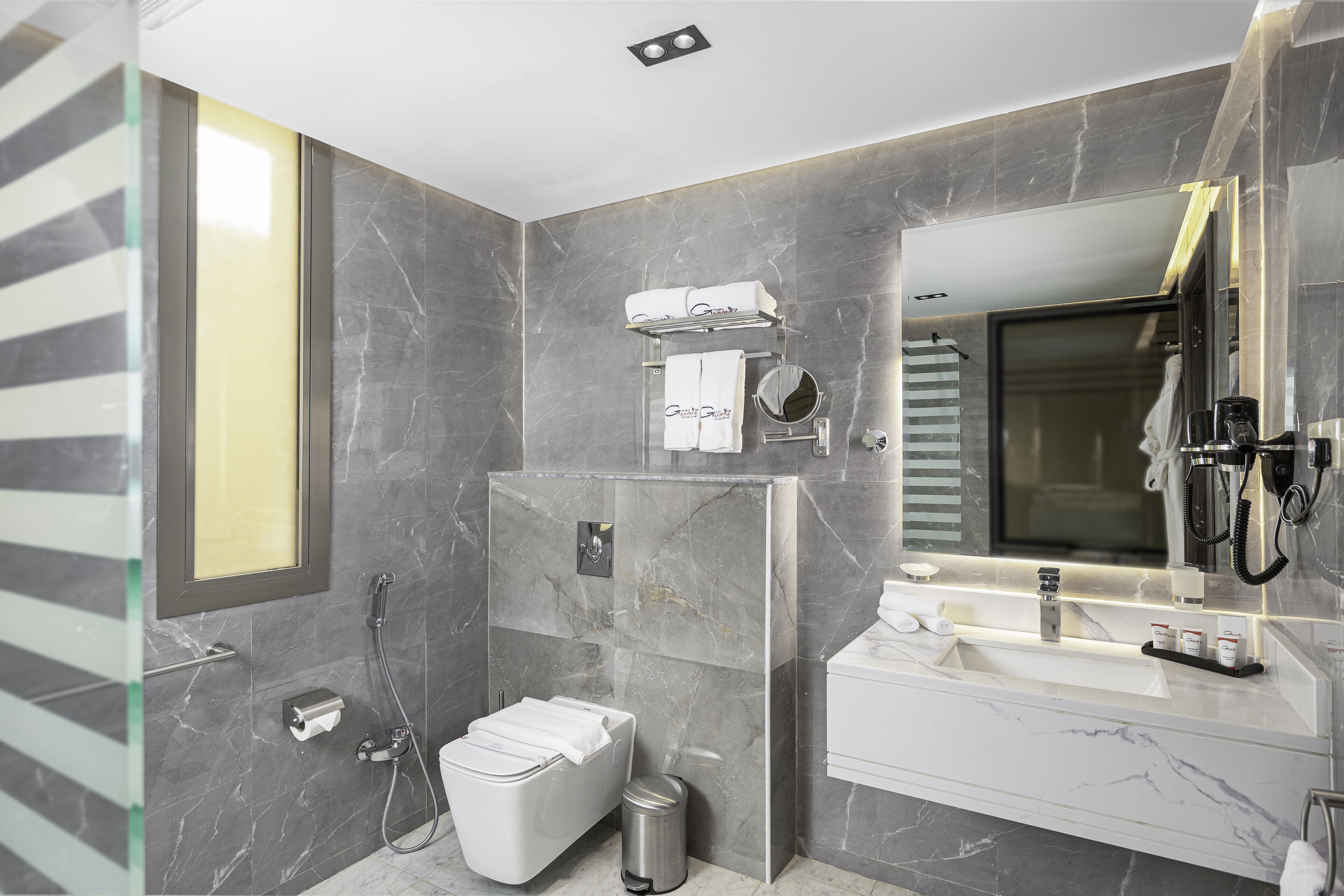 Une salle de bain moderne avec un grand miroir, un lavabo encastré et des toilettes.