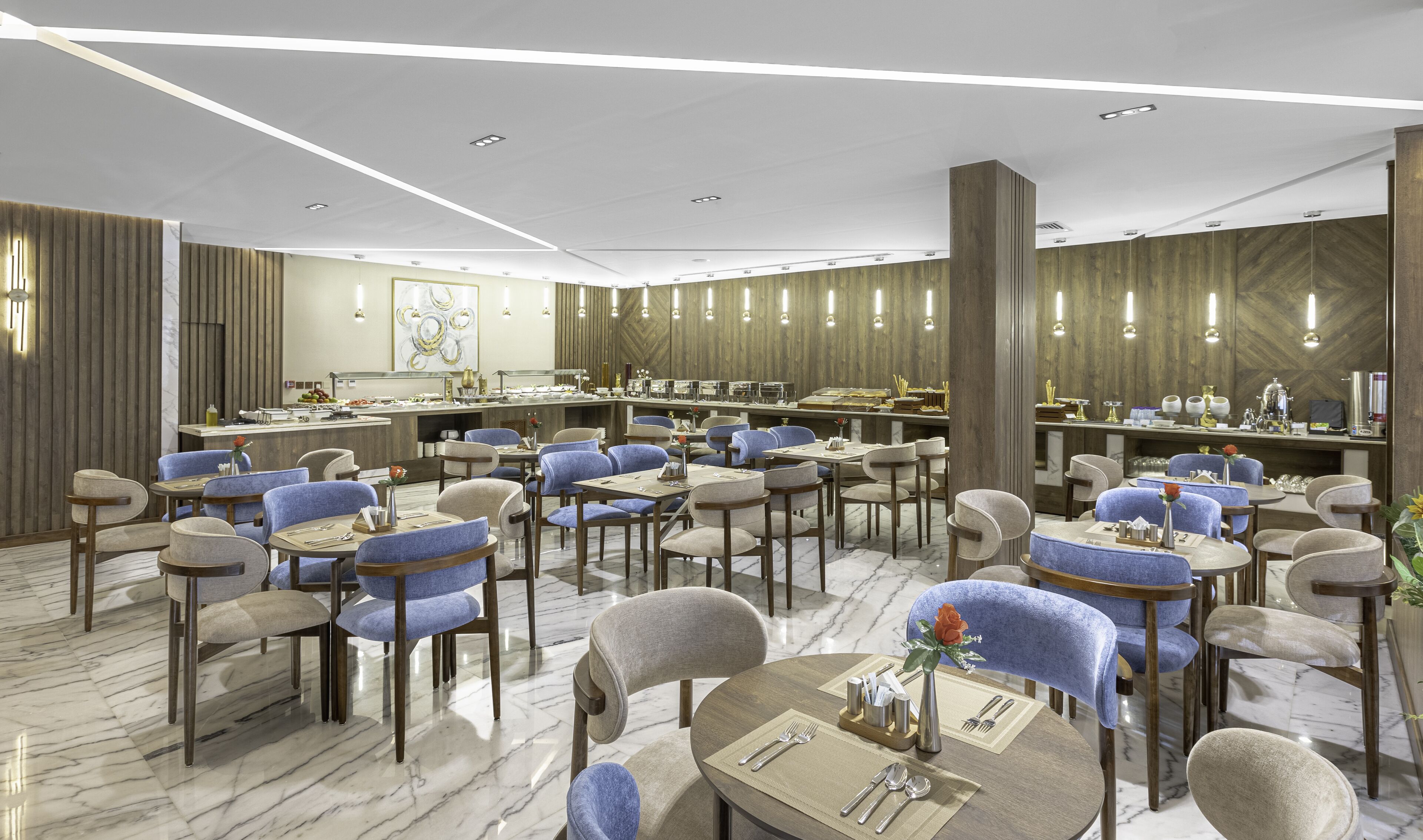 Uma sala de jantar moderna com piso de mármore, diversas mesas de jantar com cadeiras estofadas em azul e uma área de buffet central.