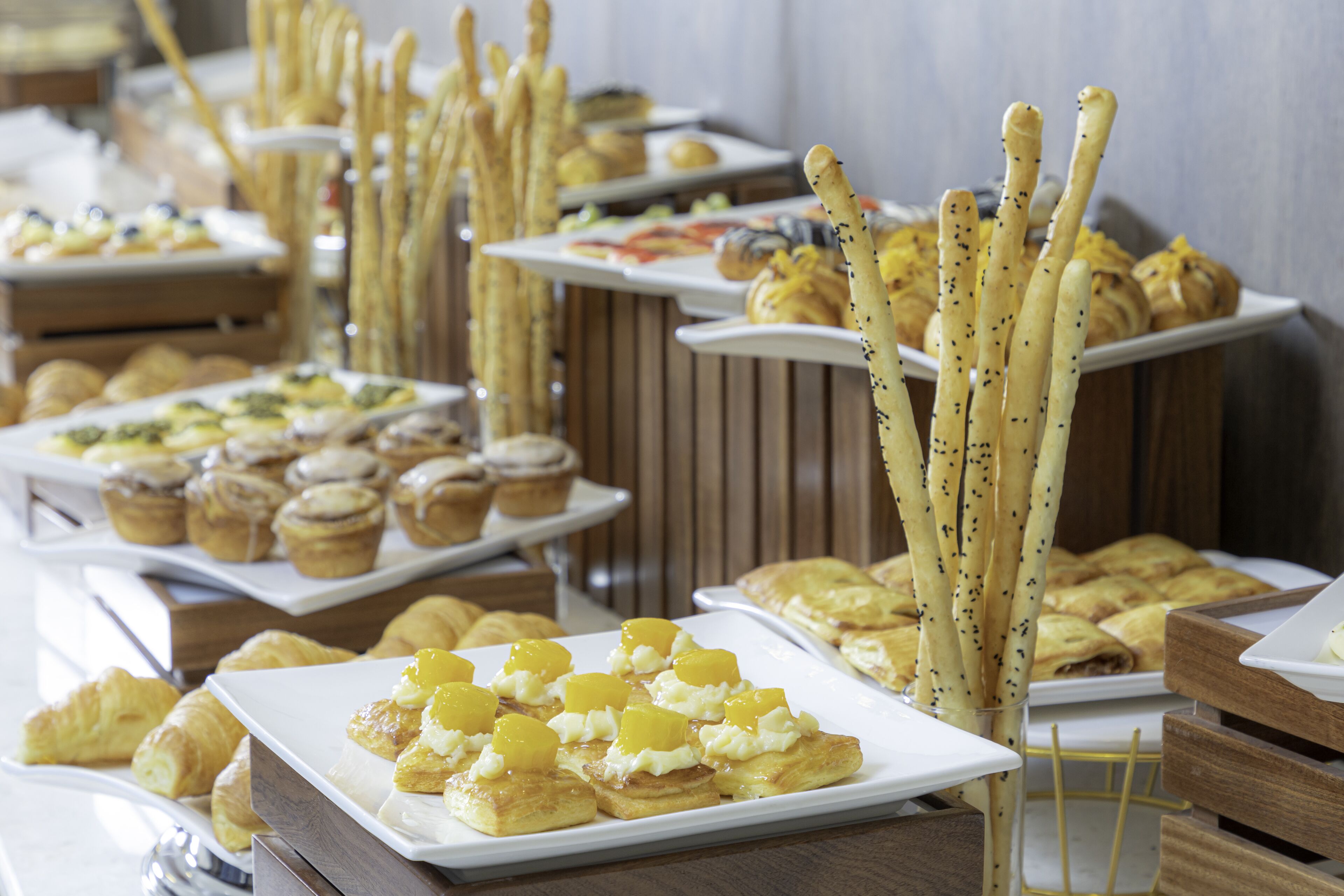 Un buffet proposant une variété de viennoiseries et de desserts, notamment des croissants et des gressins.