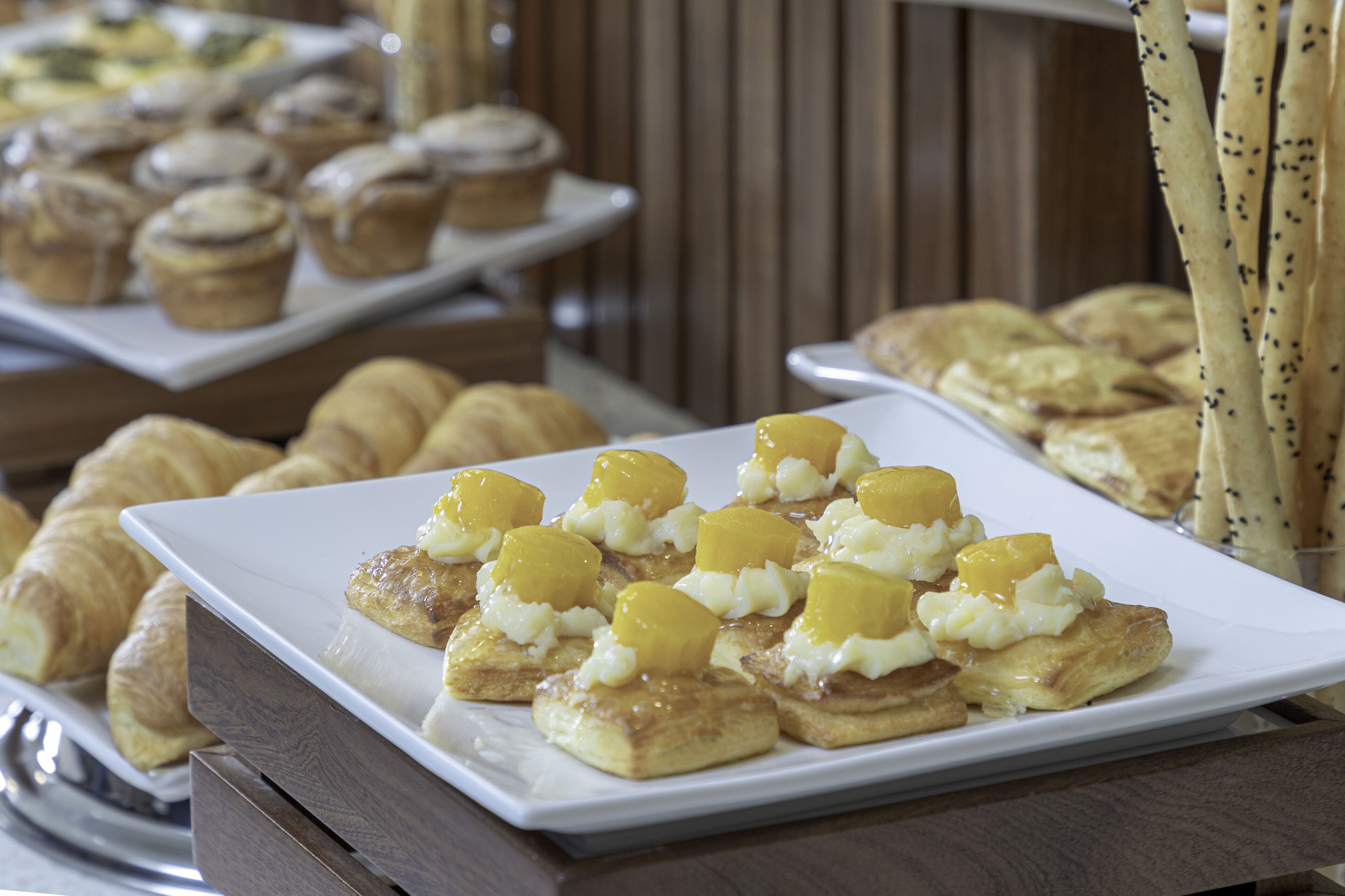 A buffet with various pastries and desserts, including croissants and fruit-topped pastries.