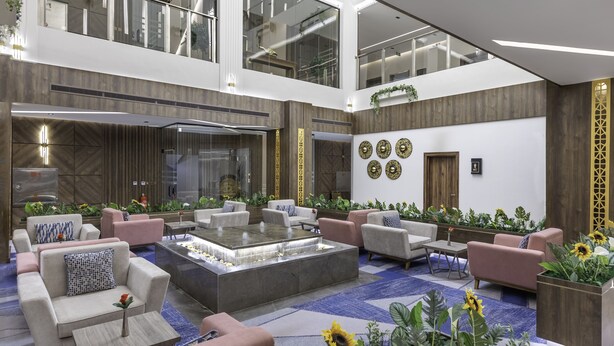 A spacious lobby with multiple seating areas, a central water feature, and a high ceiling with natural light. - Seven Gardens Hotel (Riyadh)