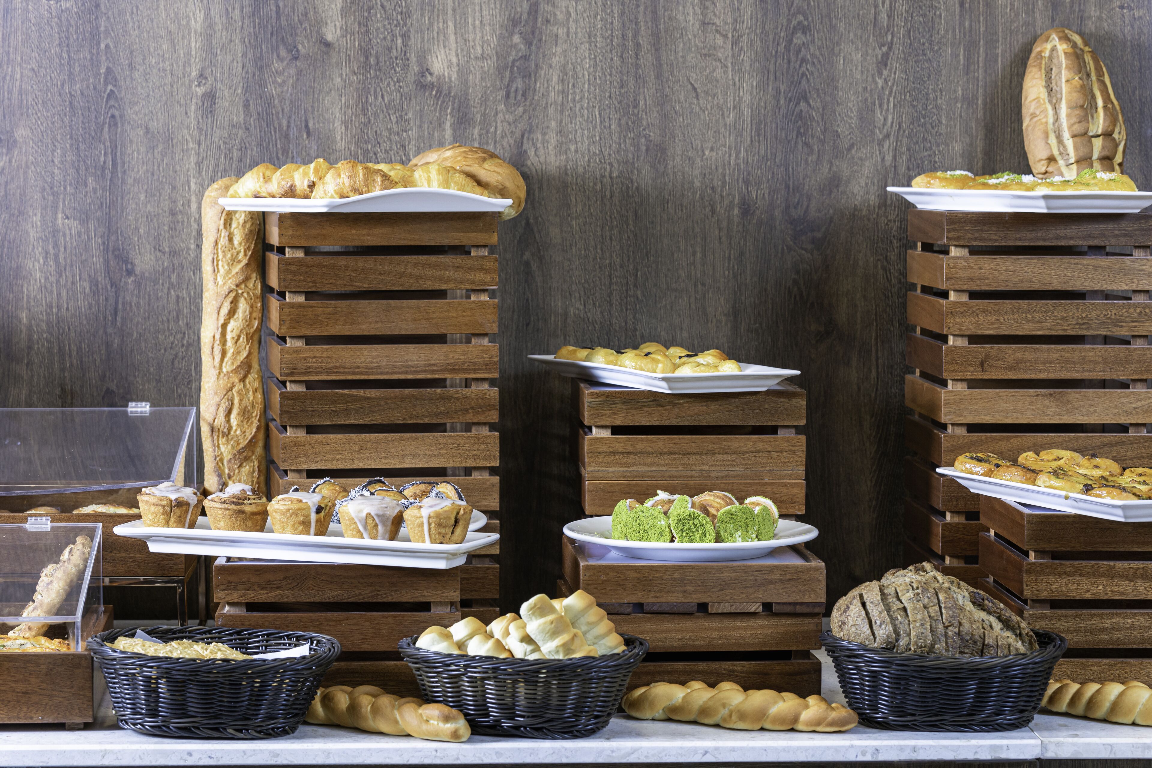 A bakery display with various breads and pastries on wooden racks.