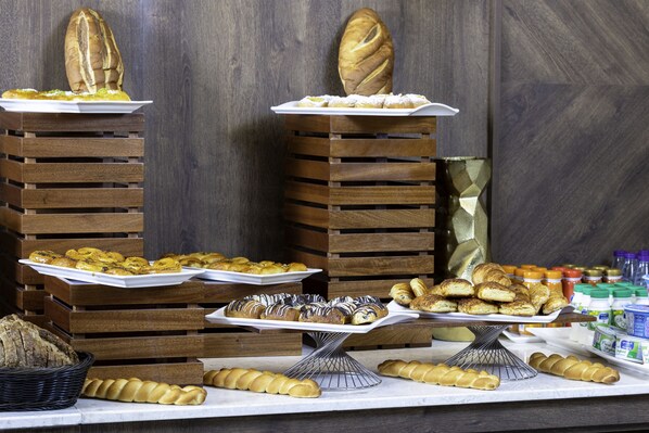 A buffet with various breads and pastries on wooden stands. - Seven Gardens Hotel (Riyadh)