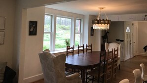 A dining area with a round table, chairs, and a chandelier. There are windows with a view of greenery outside. - Renovated historic home! (Chapel Hill)