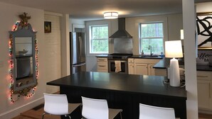 A modern kitchen with a central island, stainless steel appliances, and a large window providing natural light. - Renovated historic home! (Chapel Hill)