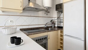 Una cocina con estufa, lavamanos y refrigerador.