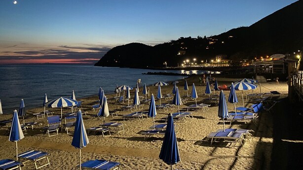 A beach with rows of sun loungers and umbrellas, a calm sea, and a hillside in the background. - Holiday Home 'Casa Luci' with Sea View, Private Terrace and Wi-Fi (Levanto)