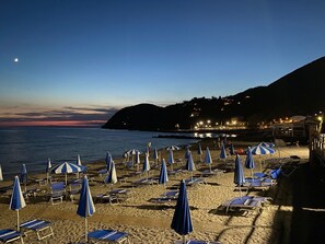 A beach with rows of sun loungers and umbrellas, a calm sea, and a hillside in the background. - Holiday Home 'Casa Luci' with Sea View, Private Terrace and Wi-Fi (Levanto)