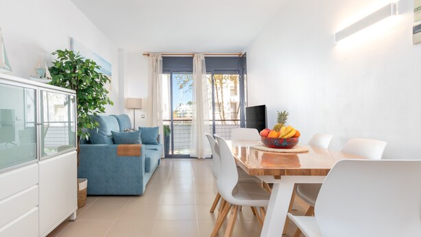 Un salon moderne avec un canapé bleu, une table à manger avec des chaises, un téléviseur et une plante.