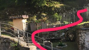 Una escalera de piedra que conduce a un pequeño edificio con barandilla de metal.