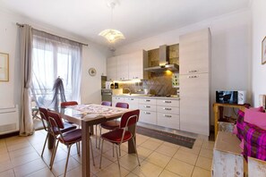 Eine moderne Küche mit weißen Schränken, einem Esstisch mit Stühlen und einem Fernseher auf einem Holzboden.