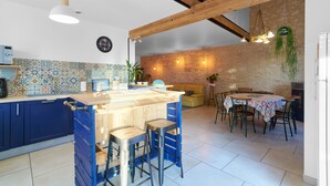 Una cocina con una isla de madera, armarios azules y un comedor con mesa y sillas.