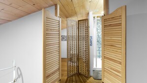 Una habitación con techo y paredes de madera, una puerta con diseño geométrico y suelo de baldosas.