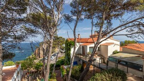 Una propiedad costera con terraza, vista al mar y tejado de tejas rojas.