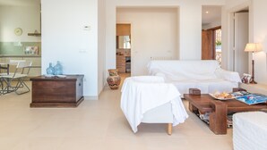 Un dormitorio moderno con cama, mesitas de noche, una mesa de centro de madera y un pequeño escritorio con silla.