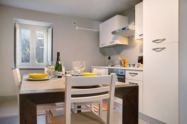 Une cuisine moderne avec des meubles blancs, une table à manger avec des assiettes jaunes et une fenêtre donnant sur des arbres.