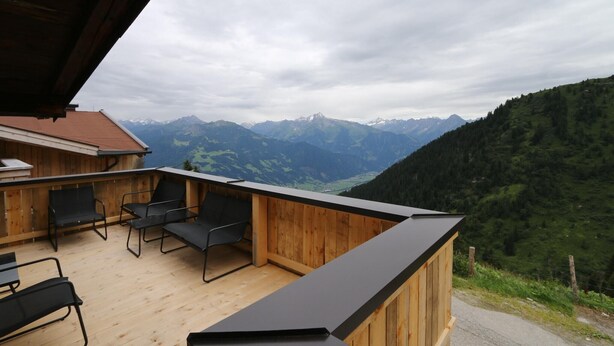 Eine Holterrasse mit Sitzgelegenheiten und Blick auf die Berge.