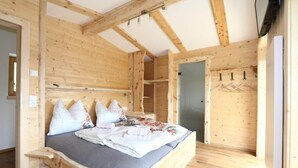 Ein Schlafzimmer aus Holz mit einem Bett, einem Kleiderschrank und einer Tür.
