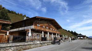 Ein Chalet-Stil-Gebäude aus Holz mit Steinuntergrund, mehreren Balkonen und Sonnenschirmen.