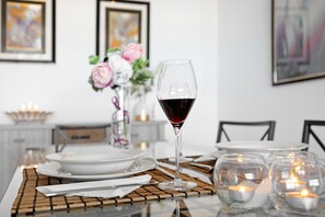 A dining table set with plates, a wine glass, candles, and a vase with flowers. - Apartment 'Summer Place' with Balcony, Wi-Fi and Air Conditioning (Portimão)