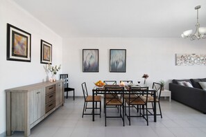 A dining area with a wooden cabinet, a dining table with chairs, and framed artwork on the walls.