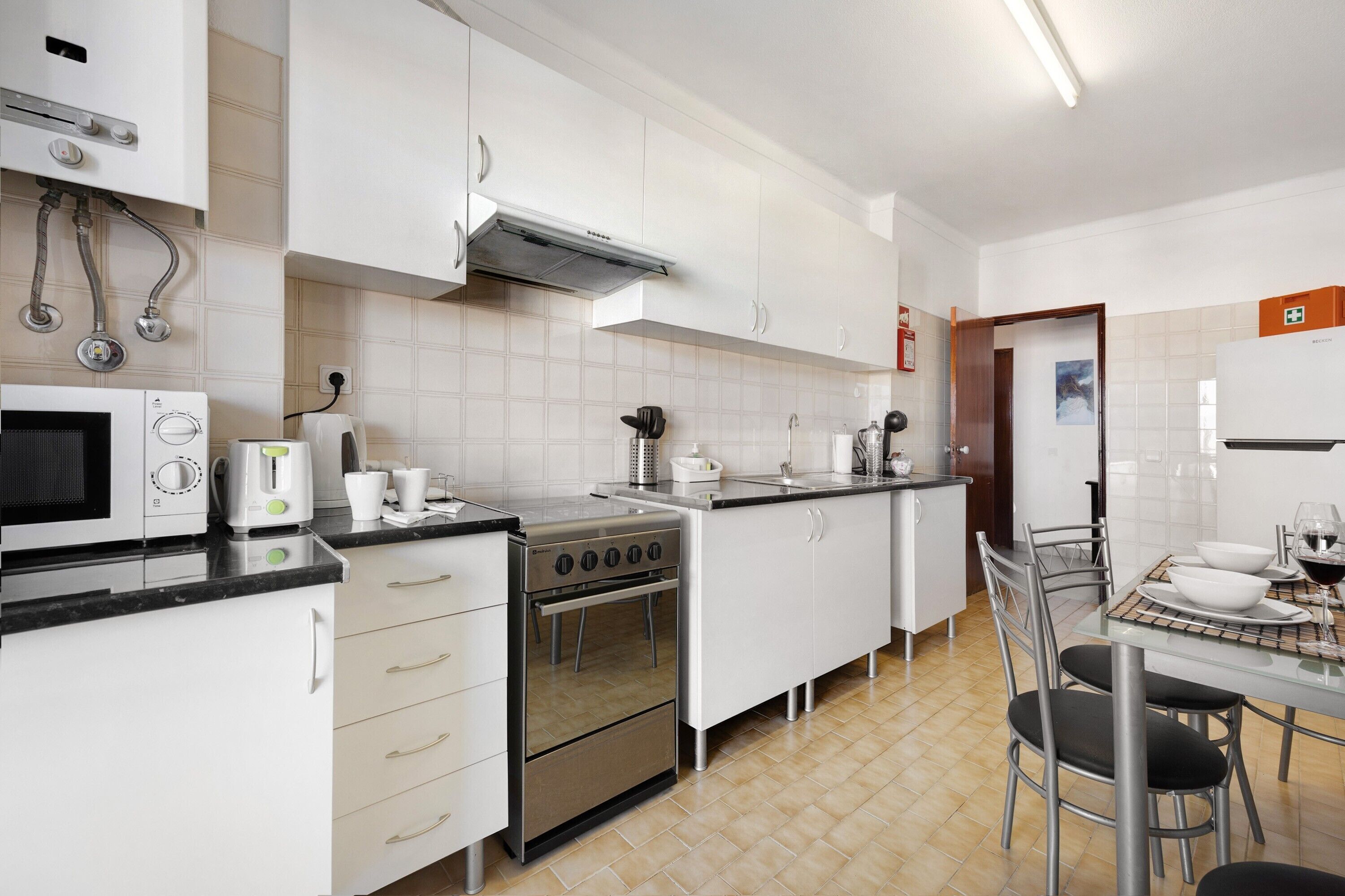 A modern kitchen with white cabinets, a stove, microwave, and a dining area with a table and chairs.
