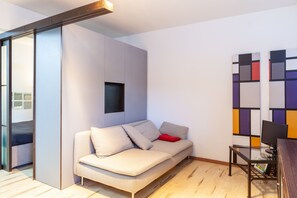 A modern living room with a sofa, a small table, and a wall art piece.