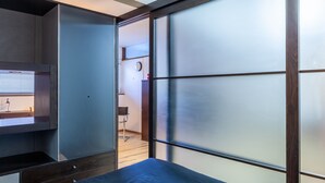 Een kamer met een schuifdeur, een bed, een bureau en een stoel.