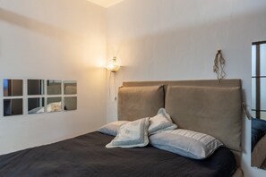A bedroom with a bed, a wall-mounted light, and a series of framed pictures.