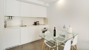 Una cocina moderna con armarios blancos, una mesa de comedor de vidrio y un horno empotrado.