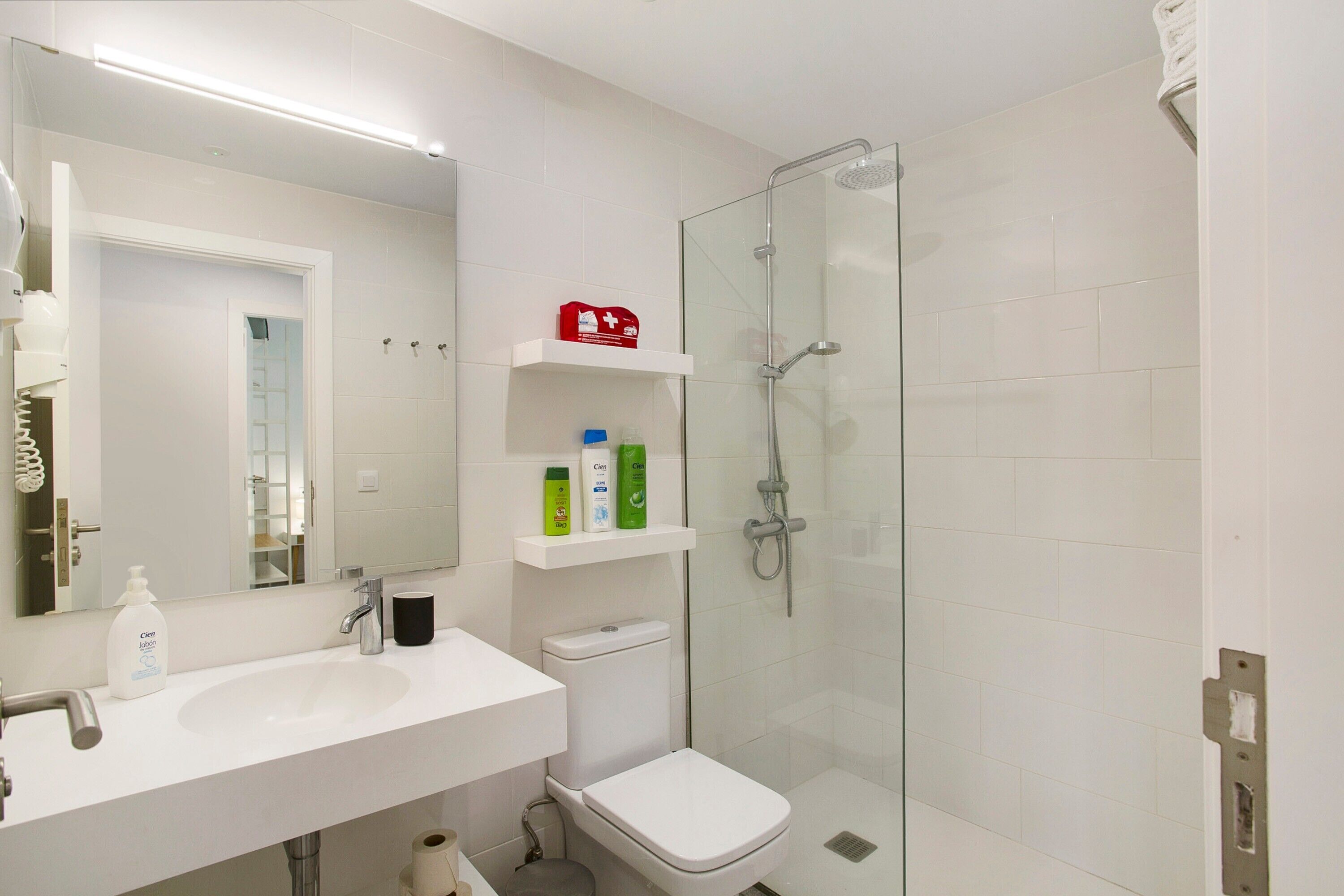 Un baño con lavamanos blanco, inodoro y ducha con cerramiento de vidrio.
