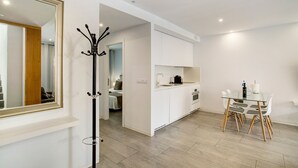 Una cocina moderna con armarios blancos, una mesa de comedor de vidrio y un perchero.