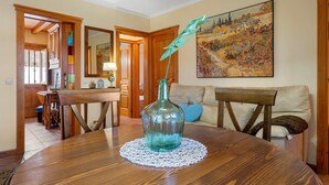 Un comedor con una mesa de madera, una botella de vidrio y un cuadro en la pared.