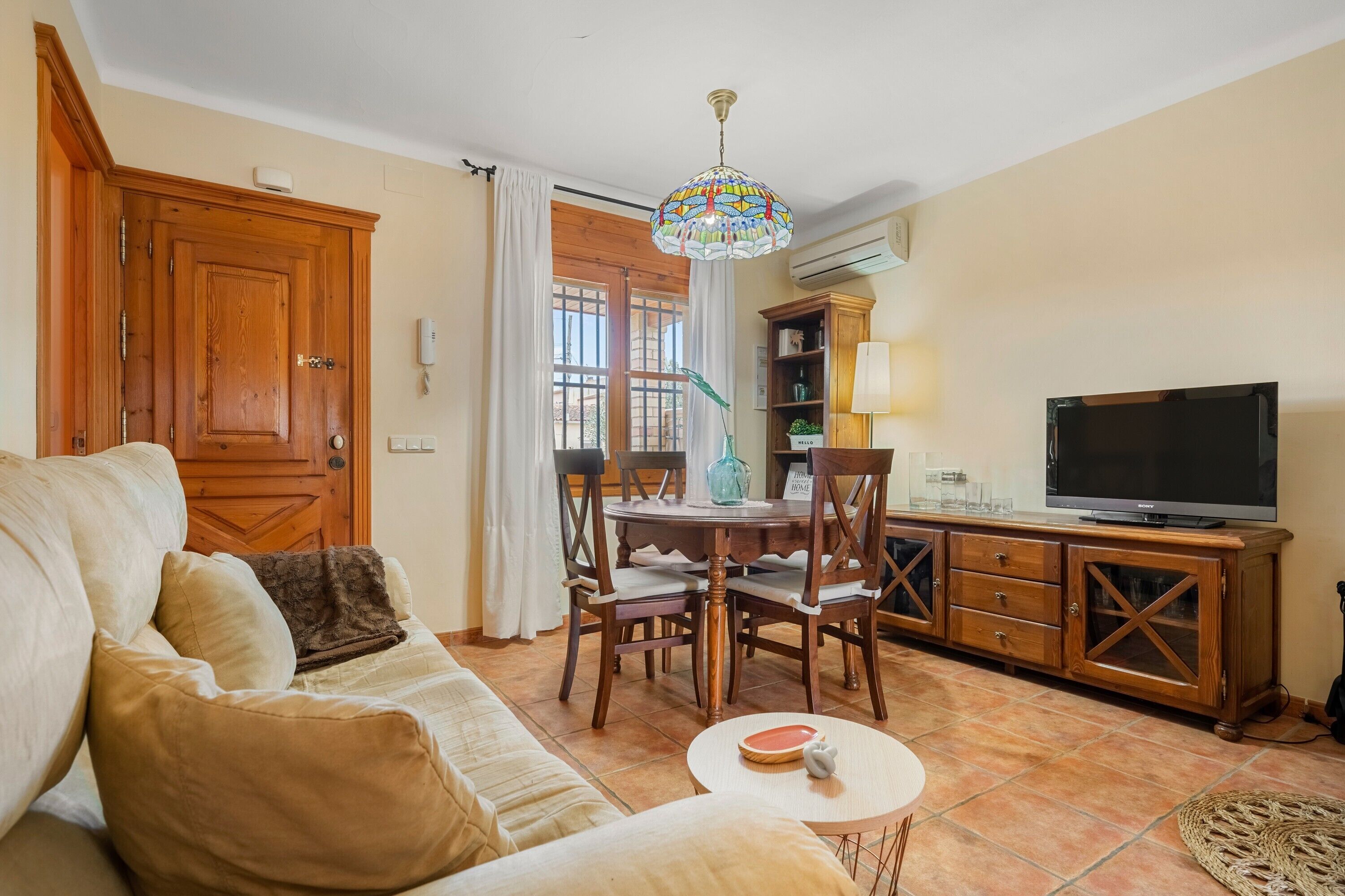 Una sala de estar con un sofá, una mesa de comedor, sillas, un televisor y un mueble de madera.