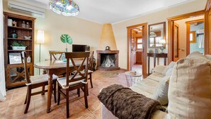 Una sala de estar con chimenea, una mesa de comedor con sillas, un sofá y una araña.