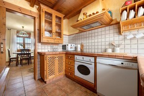 Eine Küche mit Holzschränken, einem Geschirrspüler von Bosch, einer Mikrowelle und einer gefliesten Spritzschutzwand.