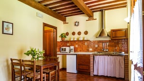 Une cuisine avec des chaises en bois, une table à manger, un réfrigérateur, un four à micro-ondes et un évier.