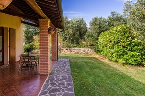 Un patio con un vialetto in pietra, un pilastro in mattoni e un tavolo con sedie.