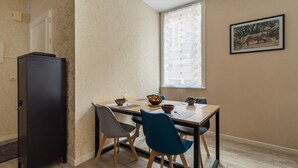 A dining area with a wooden table, four chairs, a black cabinet, and a window with blinds.