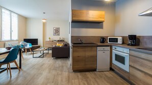 A modern kitchen with a dishwasher, microwave, and stove. There is a dining area with a table and chairs.