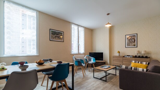A modern living room with a dining area, a TV, and a sofa.