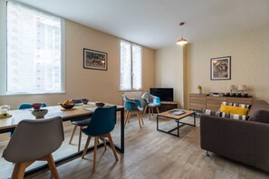 A modern living room with a dining area, a TV, and a sofa.