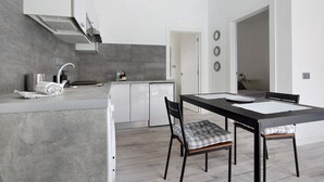 Una cocina moderna con comedor, que incluye un horno empotrado, un refrigerador y una mesa de comedor con sillas.