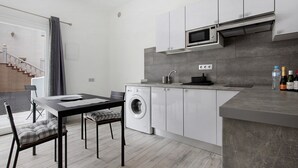 Una cocina moderna con lavadora integrada, microondas y un lavamanos.