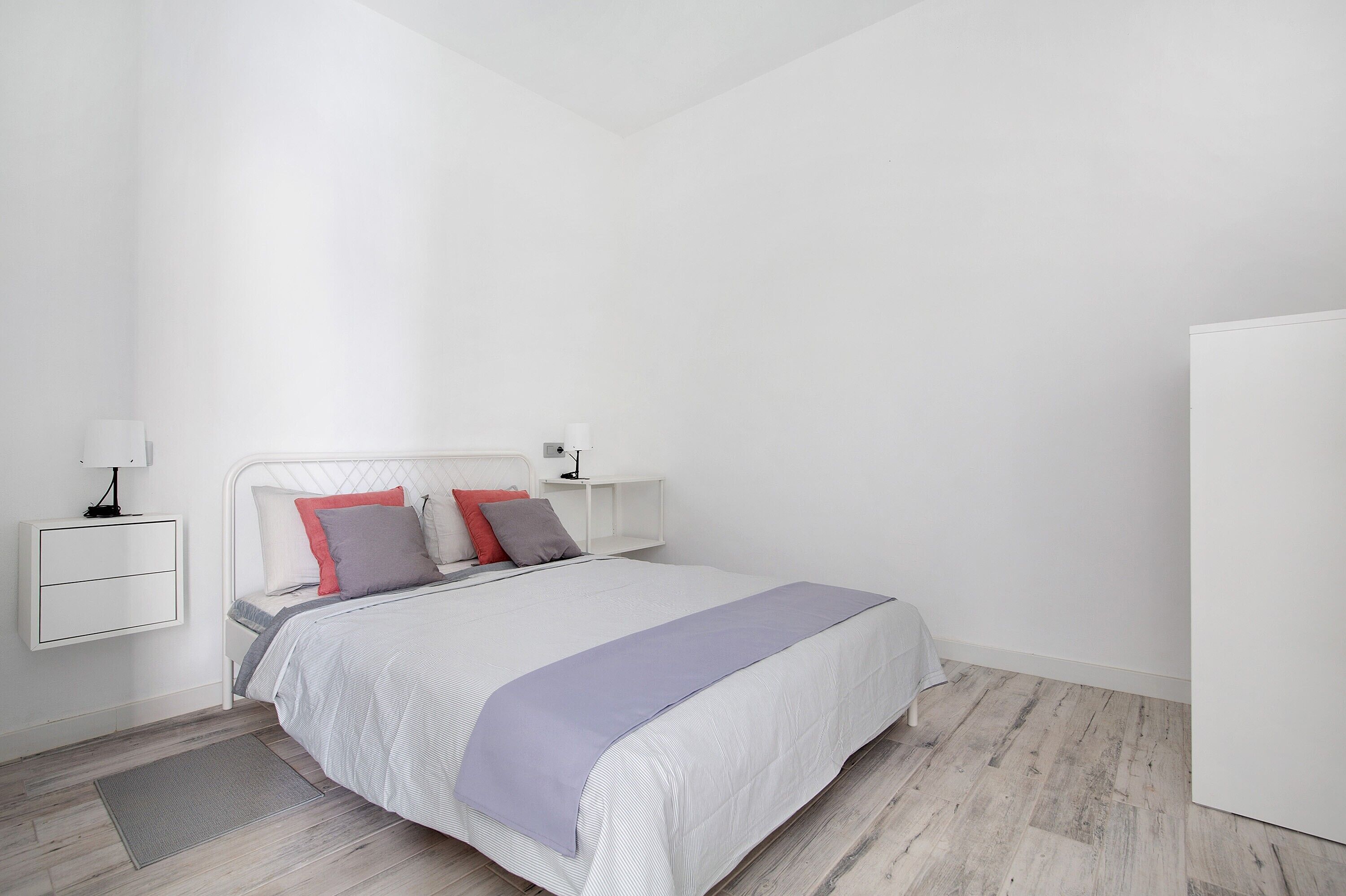 A modern bedroom with a bed, bedside tables, and a wardrobe.