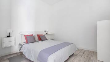 A modern bedroom with a bed, bedside tables, and a wardrobe.