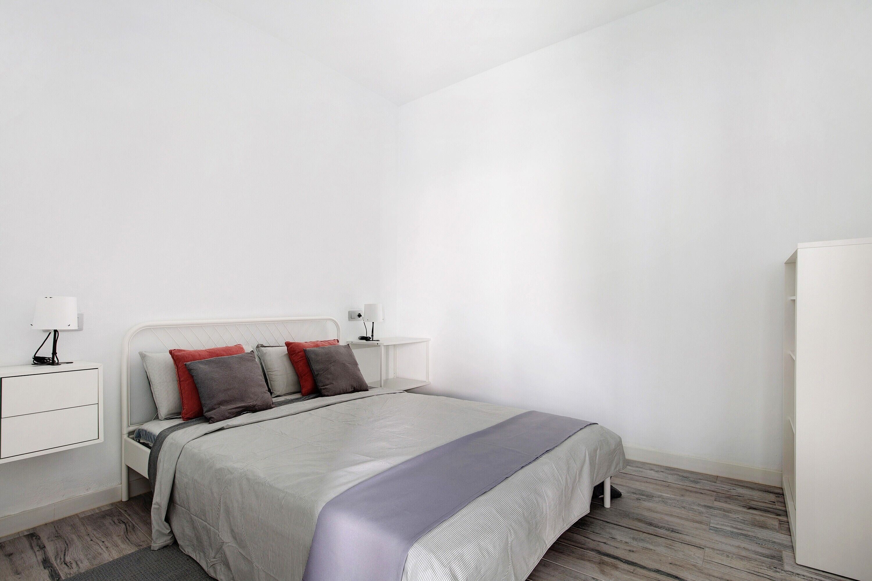 A bedroom with a bed, bedside tables, a nightstand, and a wardrobe.